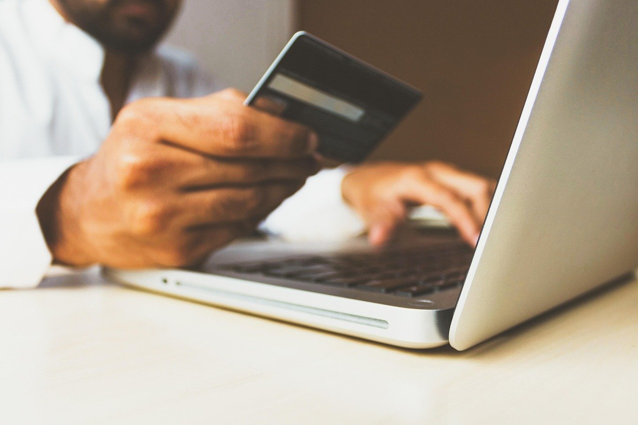 A customer holding a credit card while checking out on a laptop